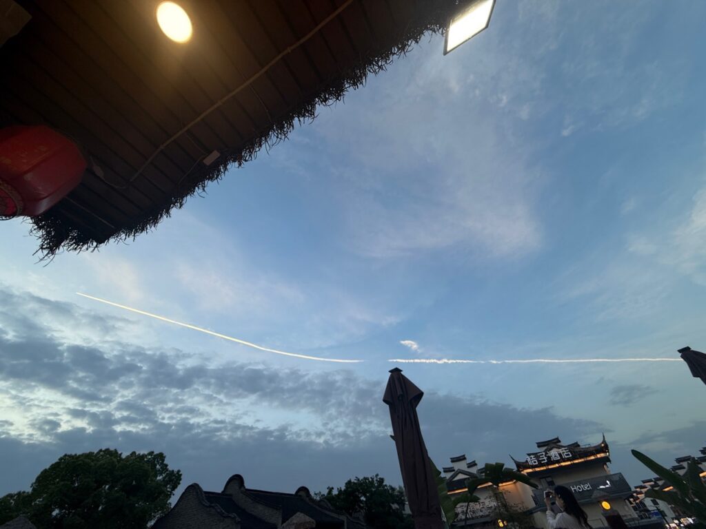 乌镇上方的傍晚天空，一道亮线穿过蓝色。