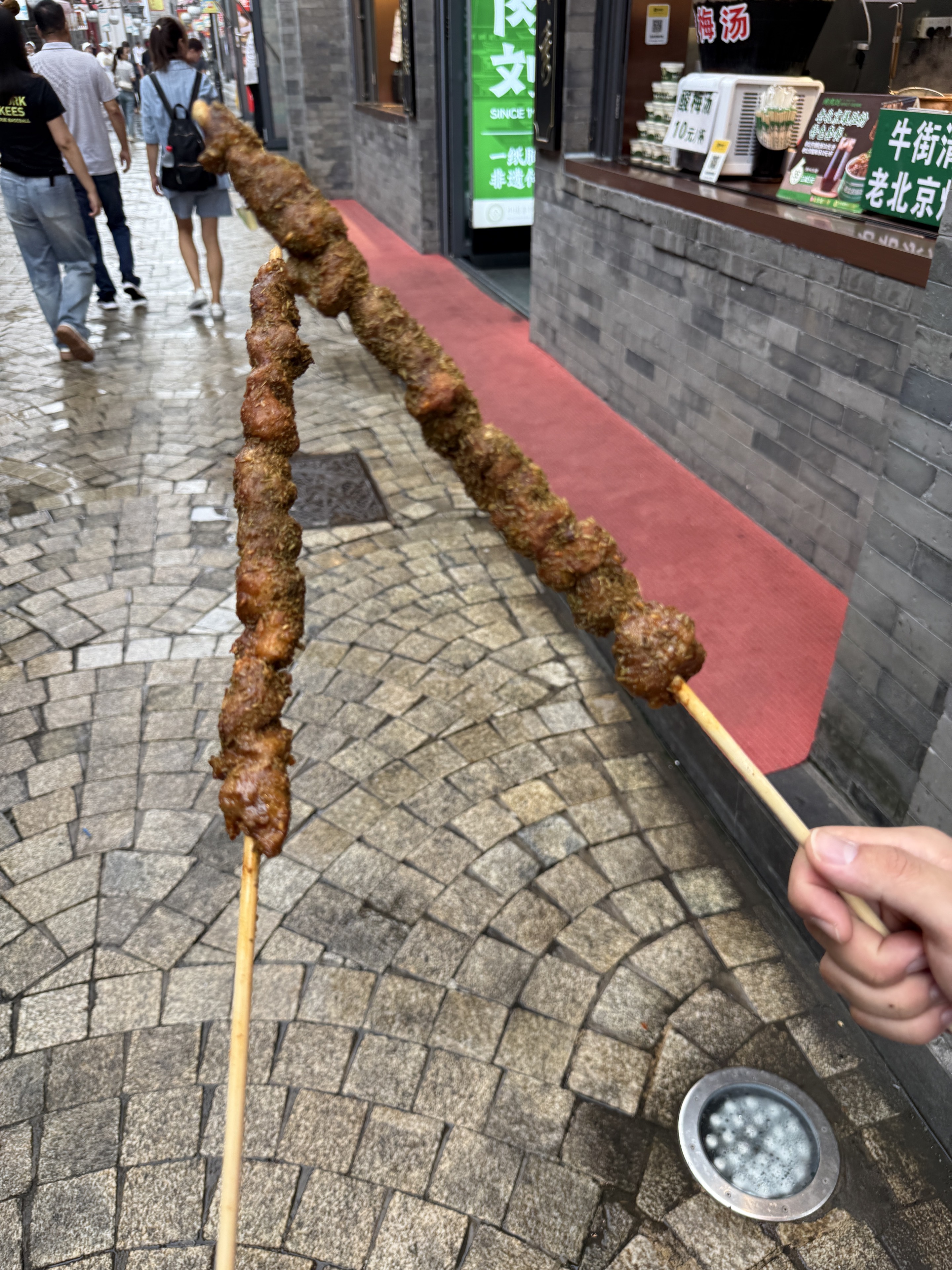 Two skewers of grilled meat on the old street.