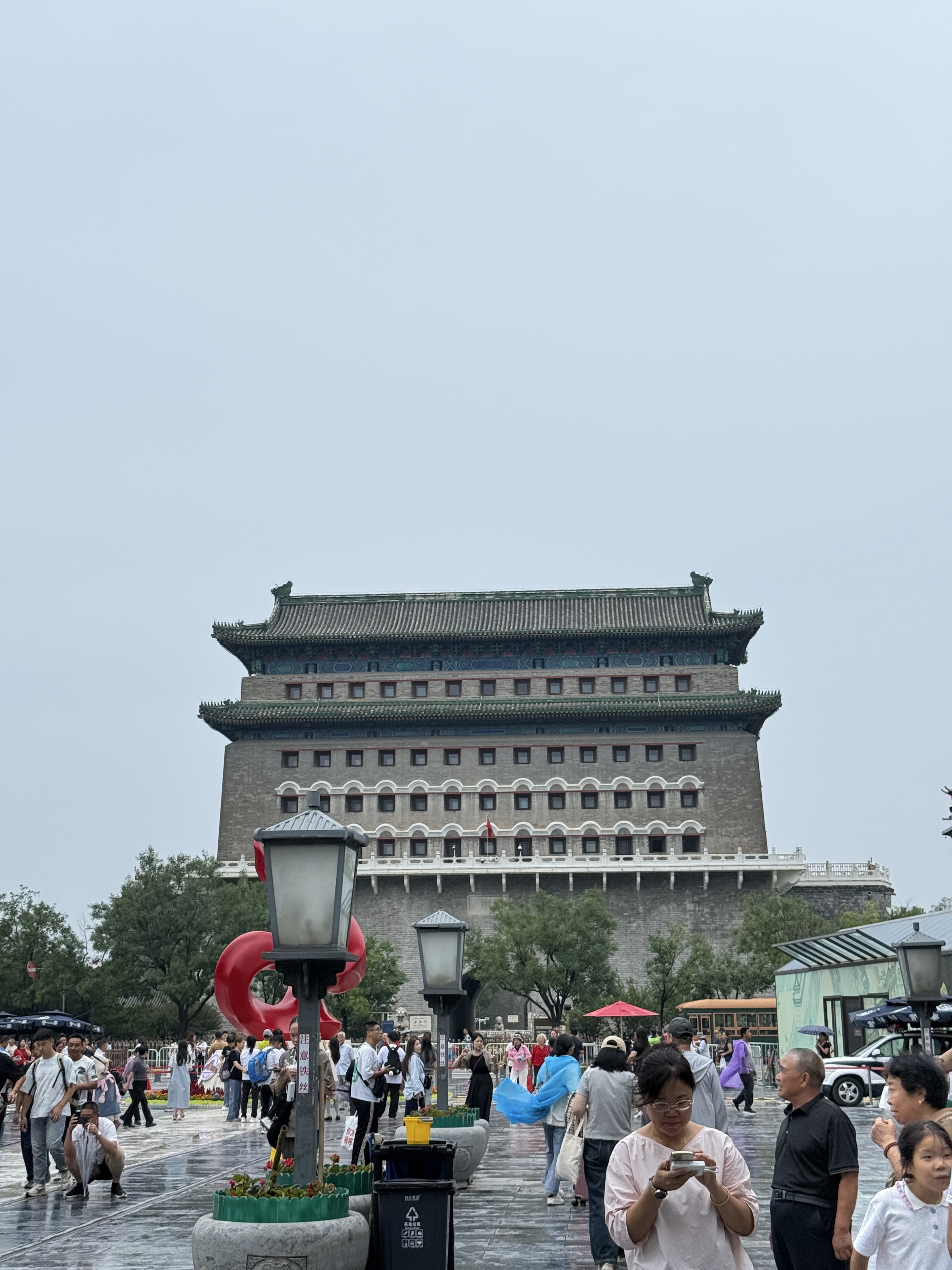 Crowds moving beneath the city gate after rain.