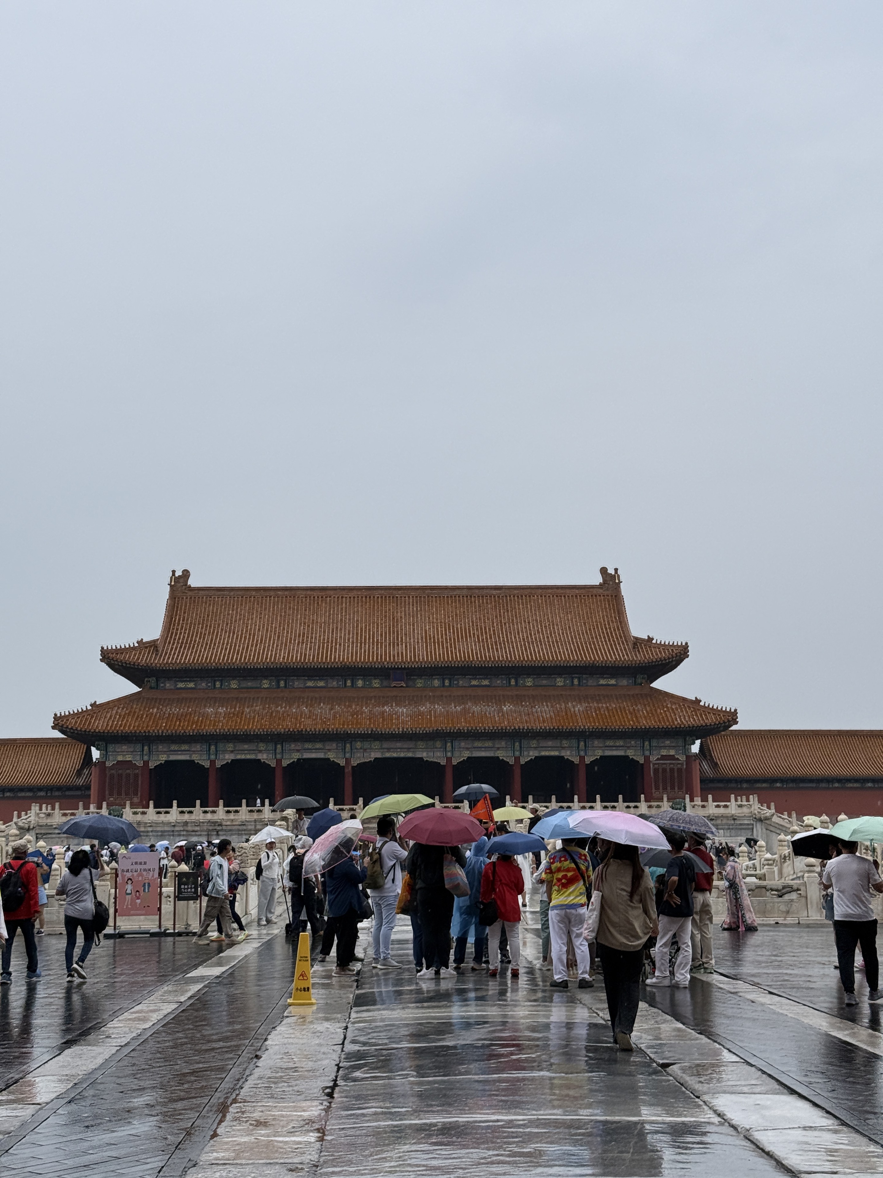 The Forbidden City in the rain, with umbrellas and wet stone paths.
